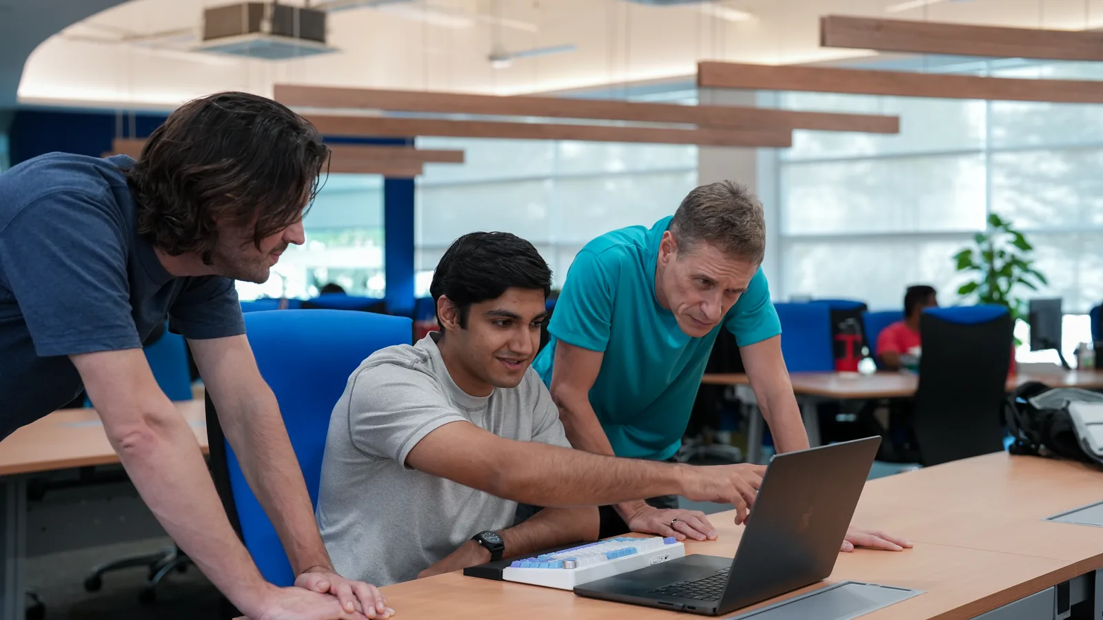 Three members of the n1 team reviewing work together at a laptop